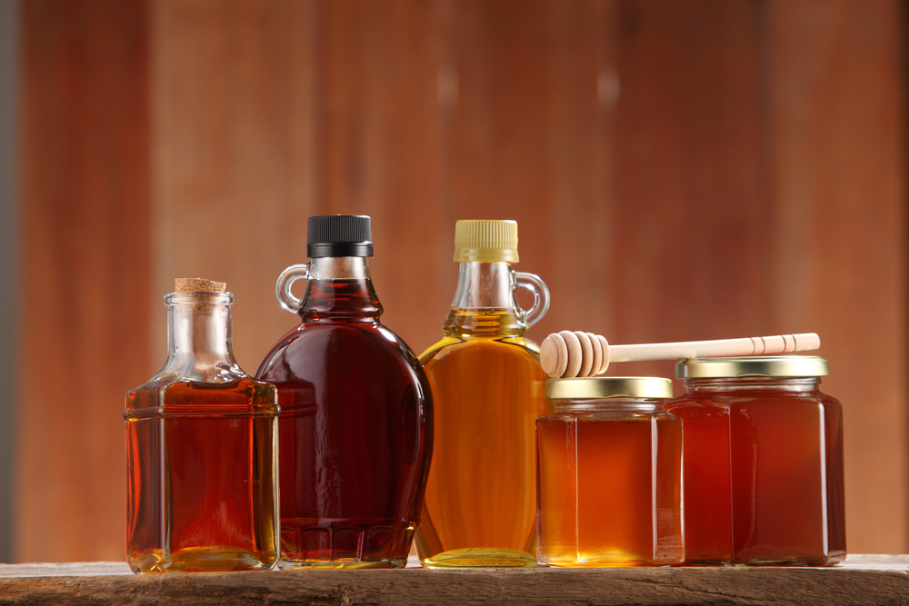 Variety of maple syrup and honey jars with honey dipper