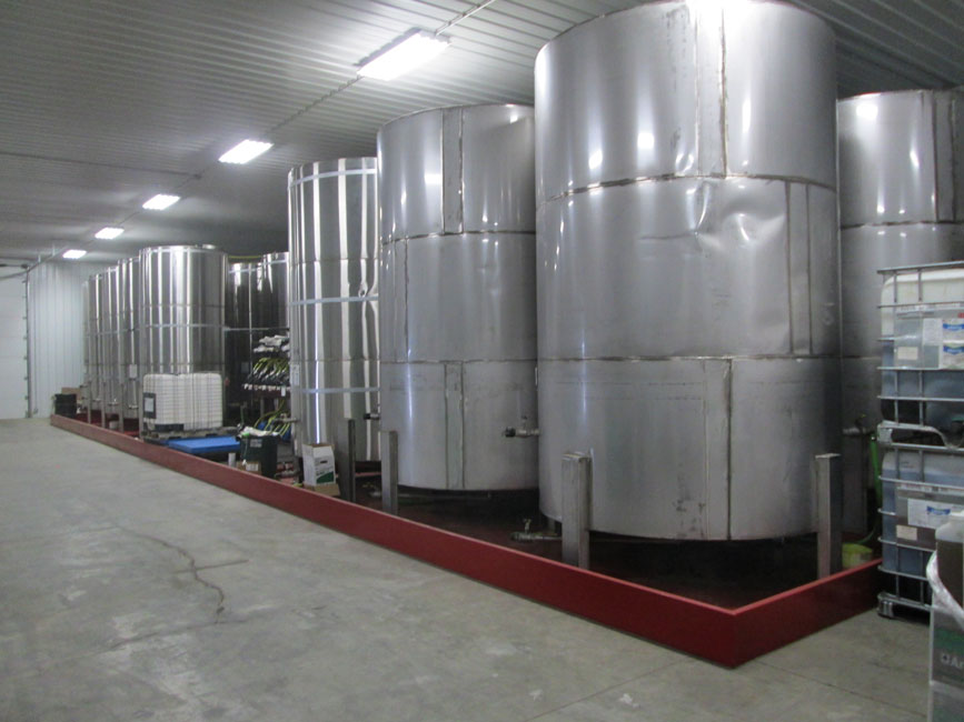 Photo shows stainless steel bulk liquid pesticide storage tanks in a metal containment dike. 