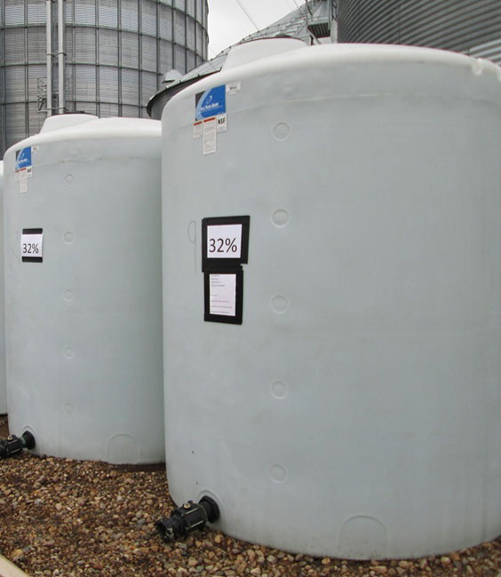 Photo shows on farm storage of two poly fertilizer tanks. 