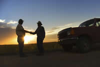 Farmers shaking hands near a truck at sunset