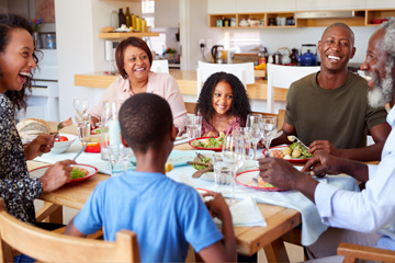 Family smiling and sitting at a dinner table.