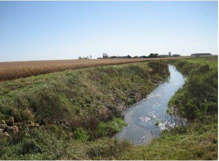 Ditch with water flowing near an agricultural field