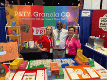 Three people standing in a colorful tradeshow booth.