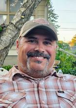 Man with a mustache and beard wearing a baseball cap and plaid shirt